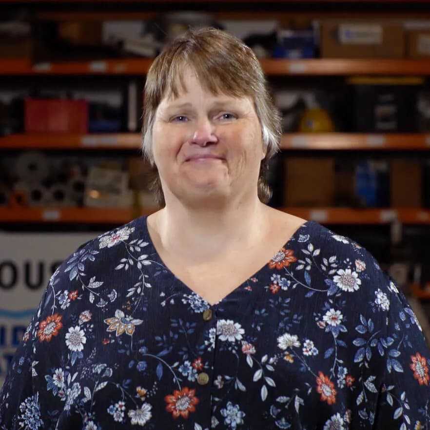 A smiling employee-owner in front of inventory