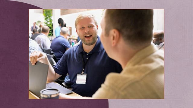 Man in blue polo opening his laptop while having a conversation