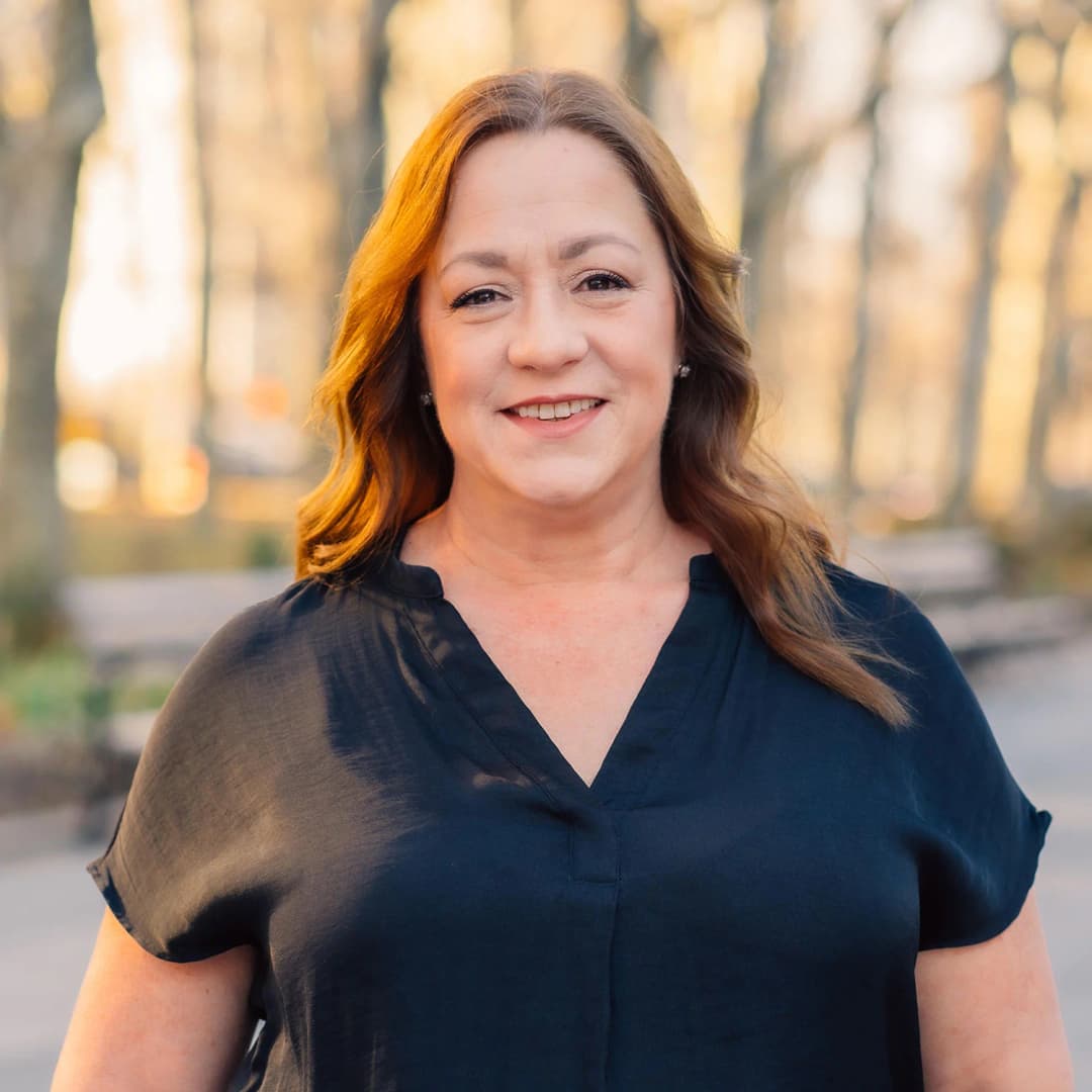 A portrait of a woman in a black shirt smiling